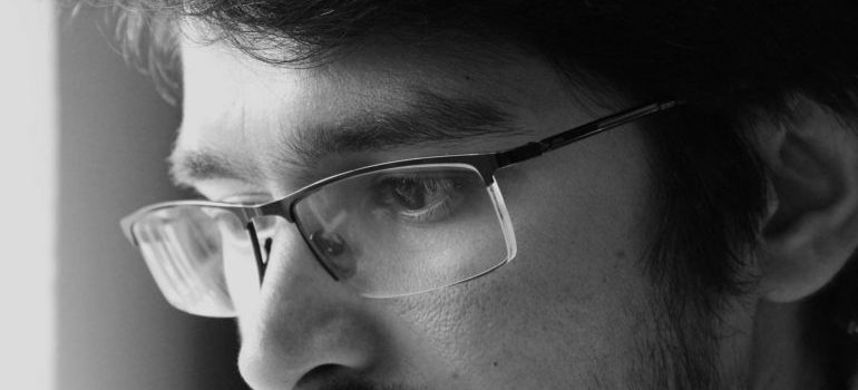 A close-up of a man with glasses lost in thought.