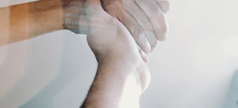 A close-up of two people holding hands in the light.