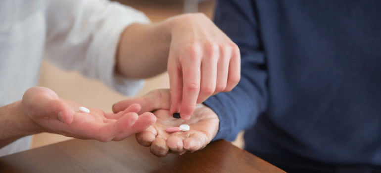 A healthcare provider placing pills on a patient’s open hand.