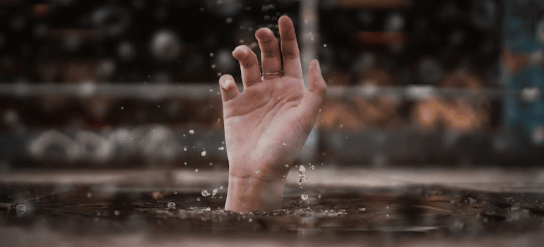 A person’s hand sticking out from a body of water.