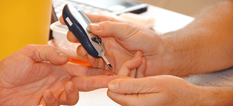 A close-up of a person drawing blood for a blood sugar test.