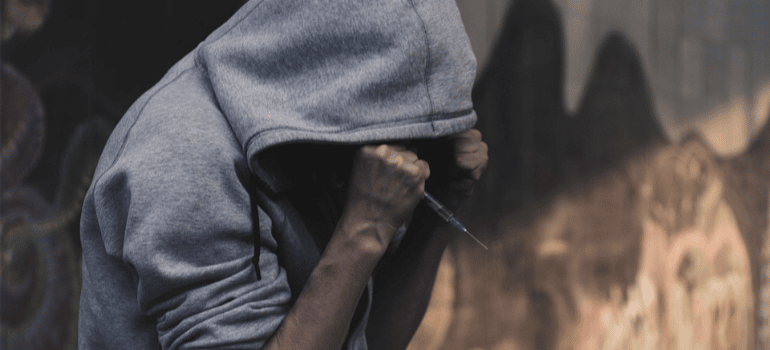 A hooded man holding a needle.
