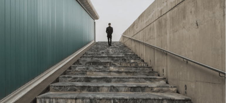 A distant photo of a person walking up the stairs outdoors.