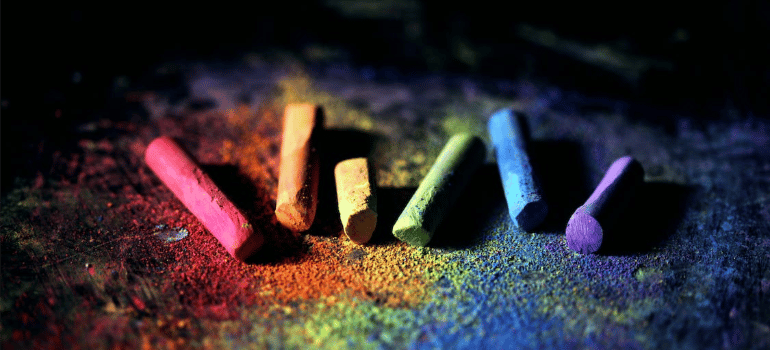 A close-up of colorful chalks on a colored surface.