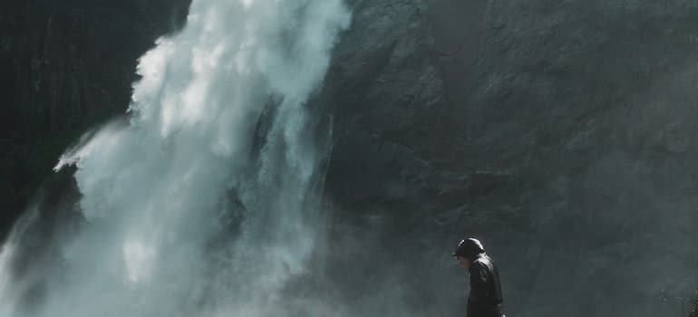 A man standing on a rock by a waterfall.