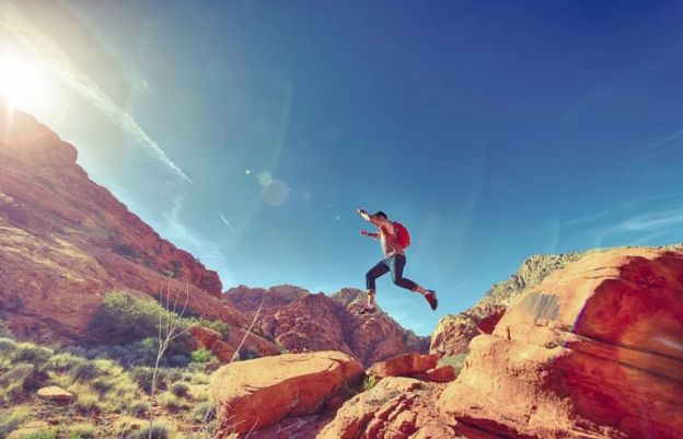 A man jumping over rocks while hiking.