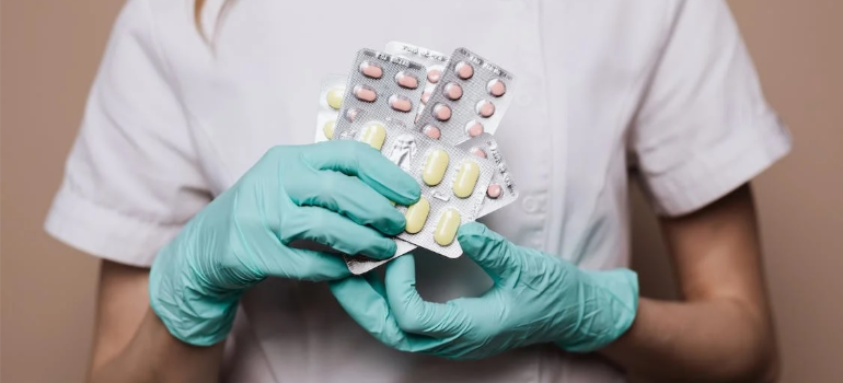 A close-up of a nurse holding an assortment of medicine pills.