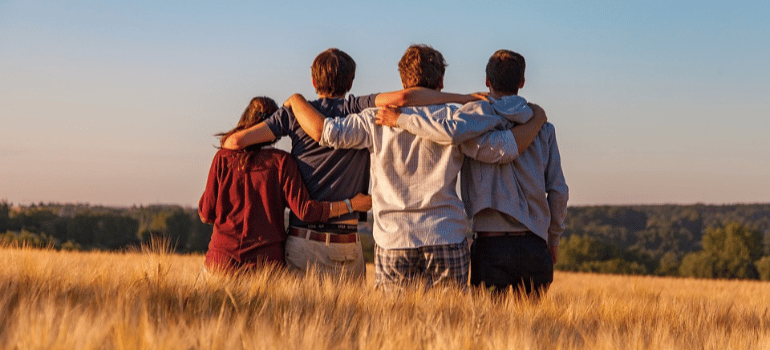 A group of friends hugging in a field.