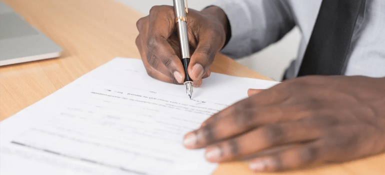 A close-up of a person signing a contract.