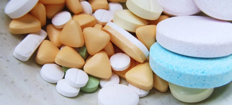 A close-up of a pile of multicolored, multi-shaped medicine pills.
