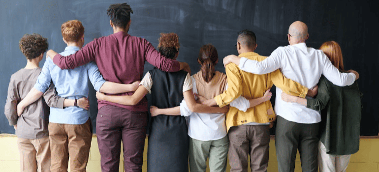 A group of people holding one another with their backs to the camera.