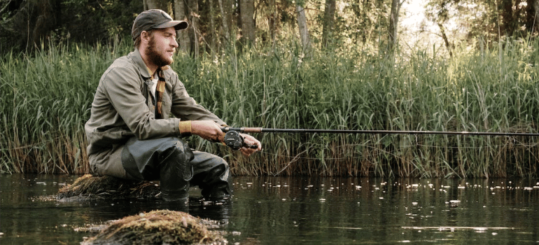A bearded man fishing in a river.