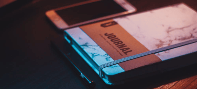 A close-up of a closed journal next to a mobile phone.