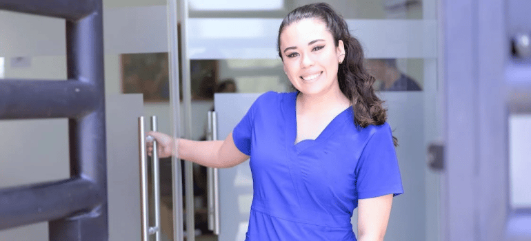 A smiling nurse in a blue scrub suit.