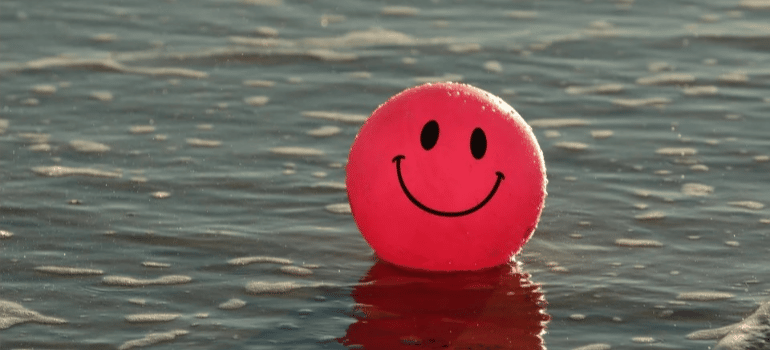 A red ball with a smiley face floating in the sea.