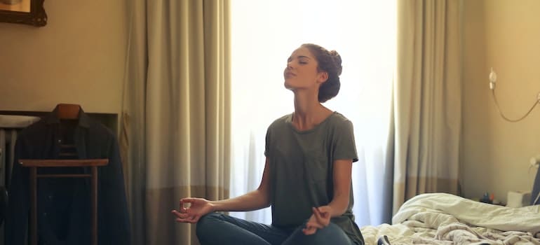 Woman meditating in her room in order to take care of your mental health during recovery in West Virginia
