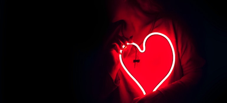 Person holding a neon heart sign.