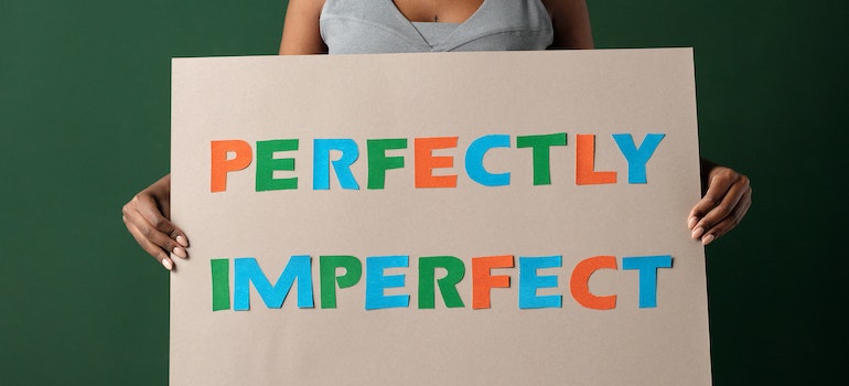 Woman holding a sign that says "perfectly imperfect".