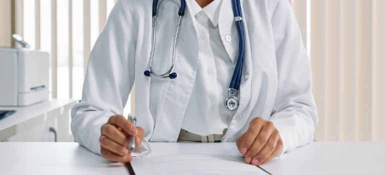 A close-up of a doctor with a stethoscope reviewing a document.