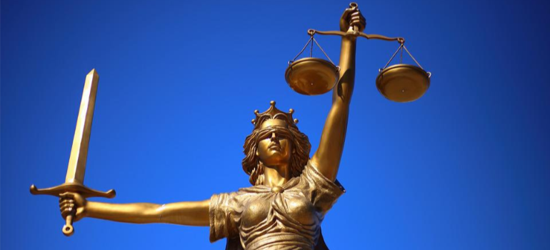 A statue of Lady Justice over a blue background.