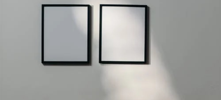 Two empty picture frames on a white wall.