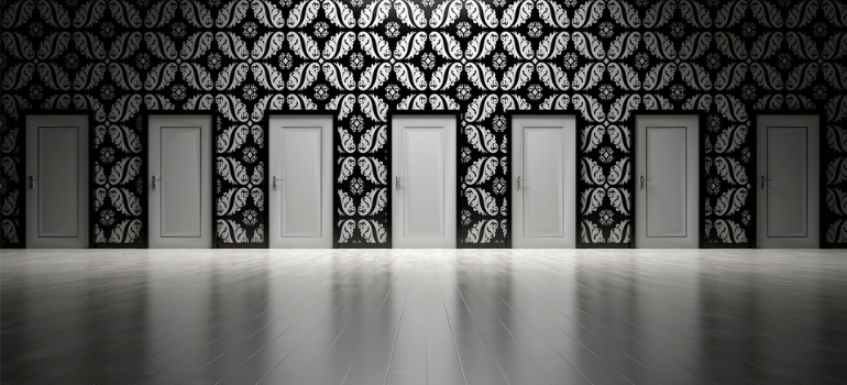 White doors in a line over a black-and-white patterned wall.