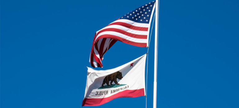 A flag pole with a US flag and a flag of the state of California.