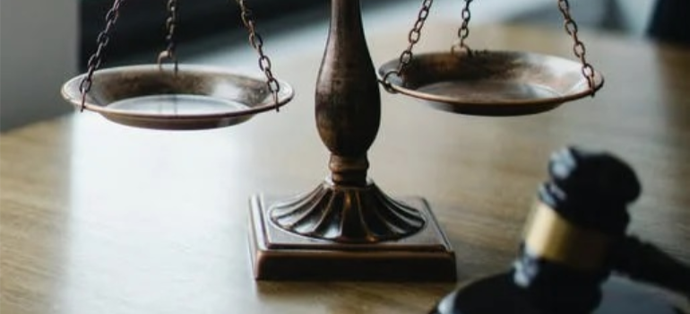 A close-up of a judgment scale and gavel on an office.