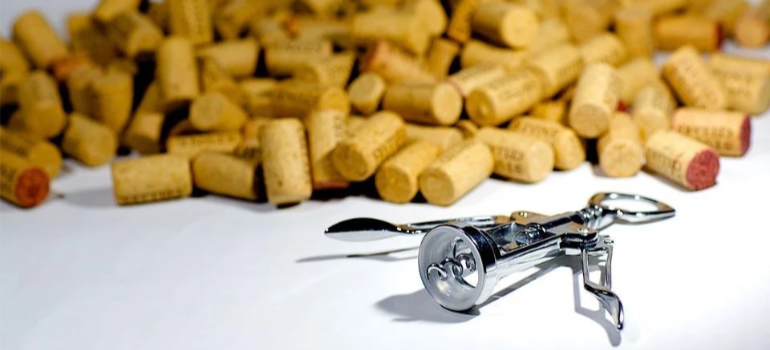 A corkscrew next to a pile of corks on a white surface showing are some professions more prone to addiction than others.