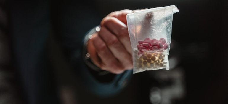A close-up of a person’s hand holding bags of illicit drugs showing are some professions more prone to addiction than others.