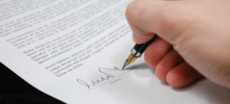 A close-up of a person signing a contract template.