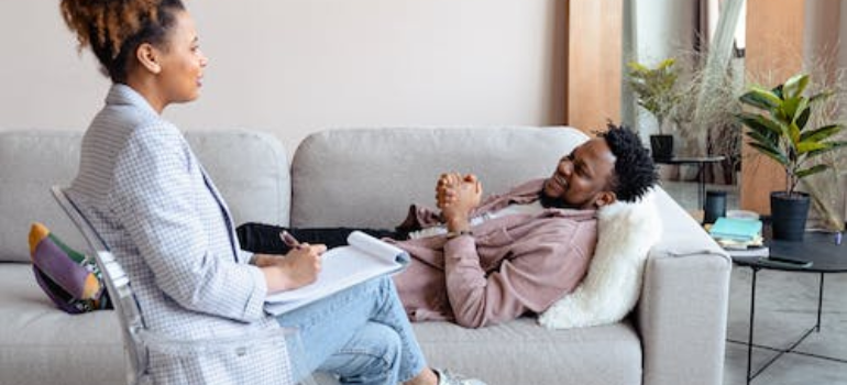 A psychotherapist and a patient lying on a couch during a therapy session.