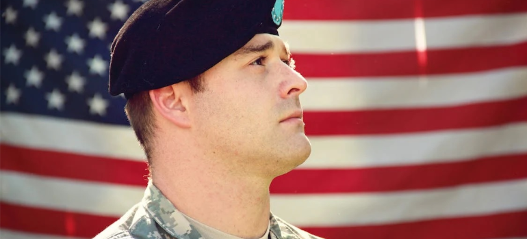 A man in military uniform in front of a US flag.