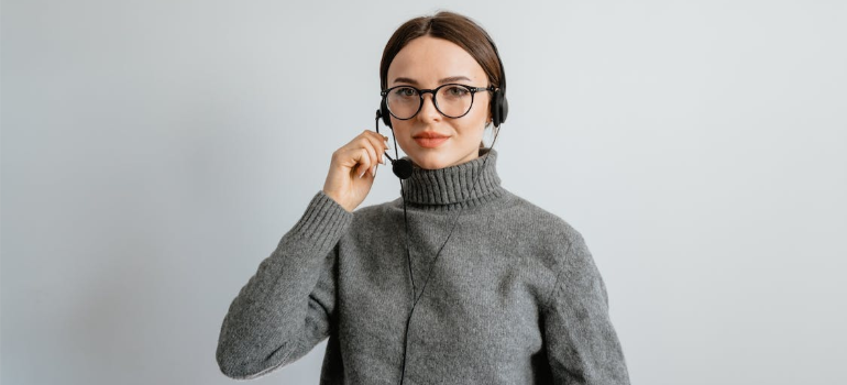A female support agent in a sweatshirt holding a headset.