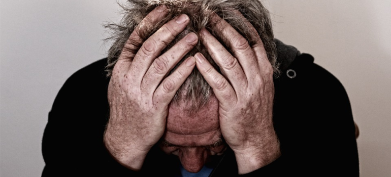 An older man holding his head in stress while struggling to prepare for a cocaine detox program in West Virginia.