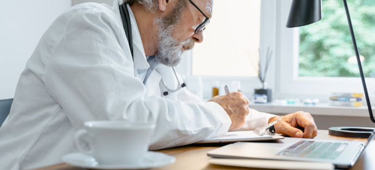 A doctor in his office writing on a paper.