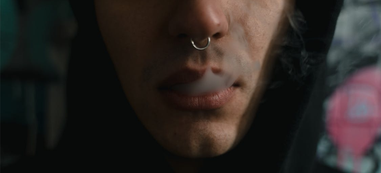 A close-up of a man with a nose ring smoking while trying to prepare for a cocaine detox program in West Virginia.