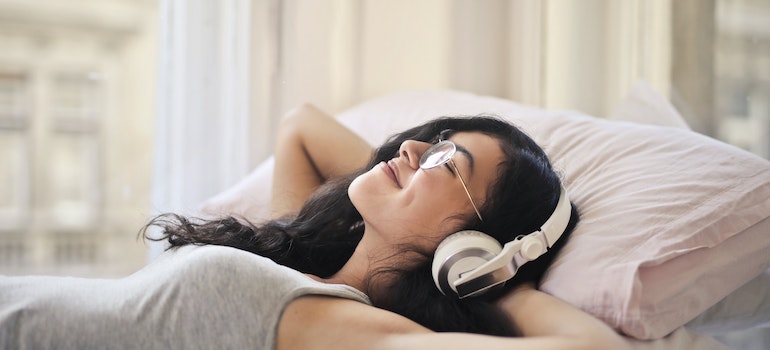 Woman lying in bed with headphones on.