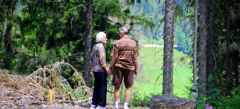 An elderly couple hiking in a forest.