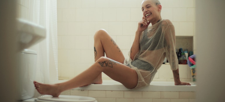 a person sitting on the bath and smiling in the bathroom