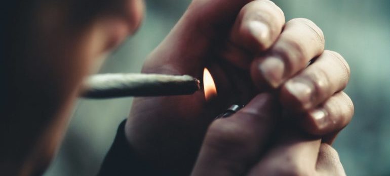 Someone smoking a joint showing the connection between self-harm and addiction.