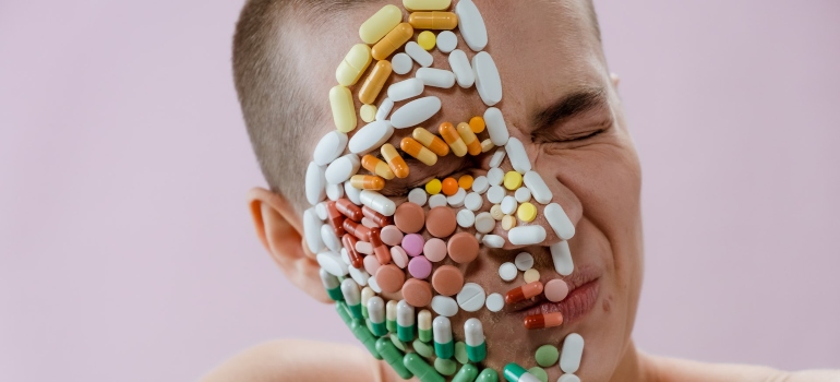 a person's face covered with pills representing the unique needs women face in recovery