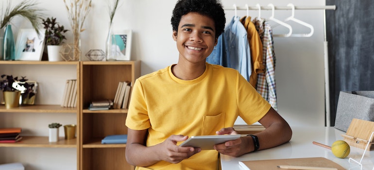 A happy teenager holding a tablet representing how to connect with your teenager to prevent drug use