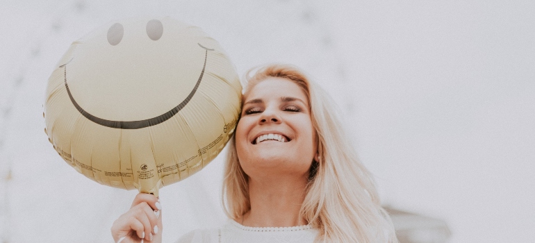 smiling woman holding a smiley balloon