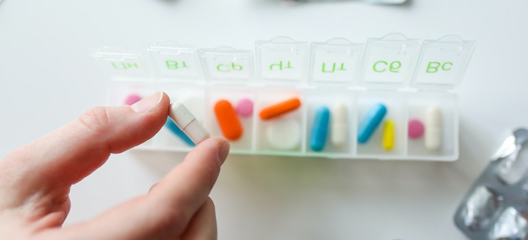 Person taking pills from a medicine organizer