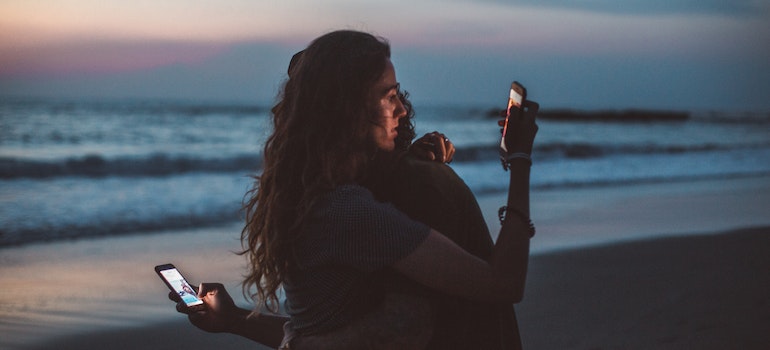 People hugging while looking at their phones.