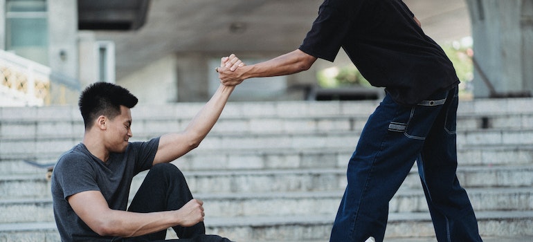 a man helping another man get up showing how spirituality supports lasting recovery