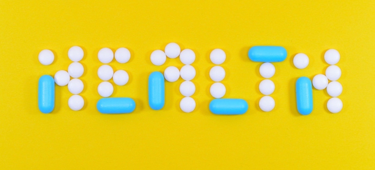 Health written with pills on a yellow surface