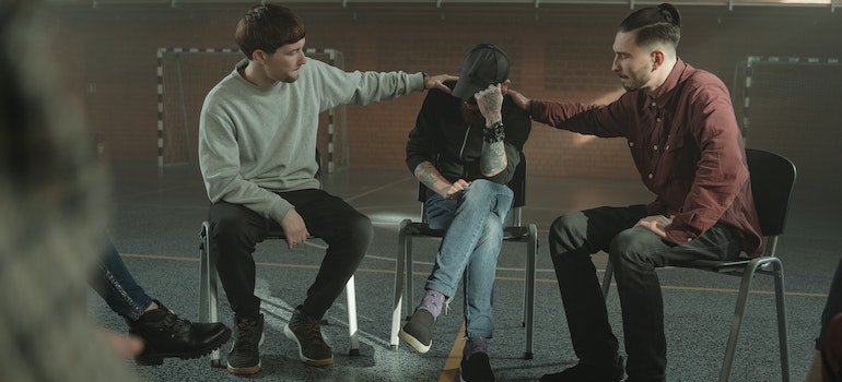 a group therapy and two people consoling a third man
