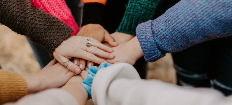 A close-up of people joining hands, illustrating the importance of support groups in addiction treatment.